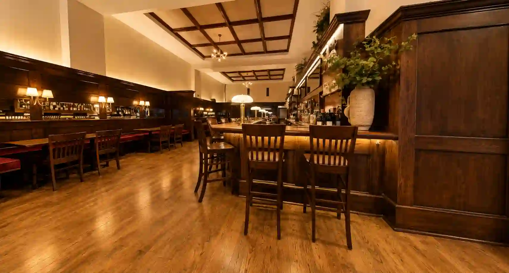 The main bar lined with wooden stools under a coffered ceiling