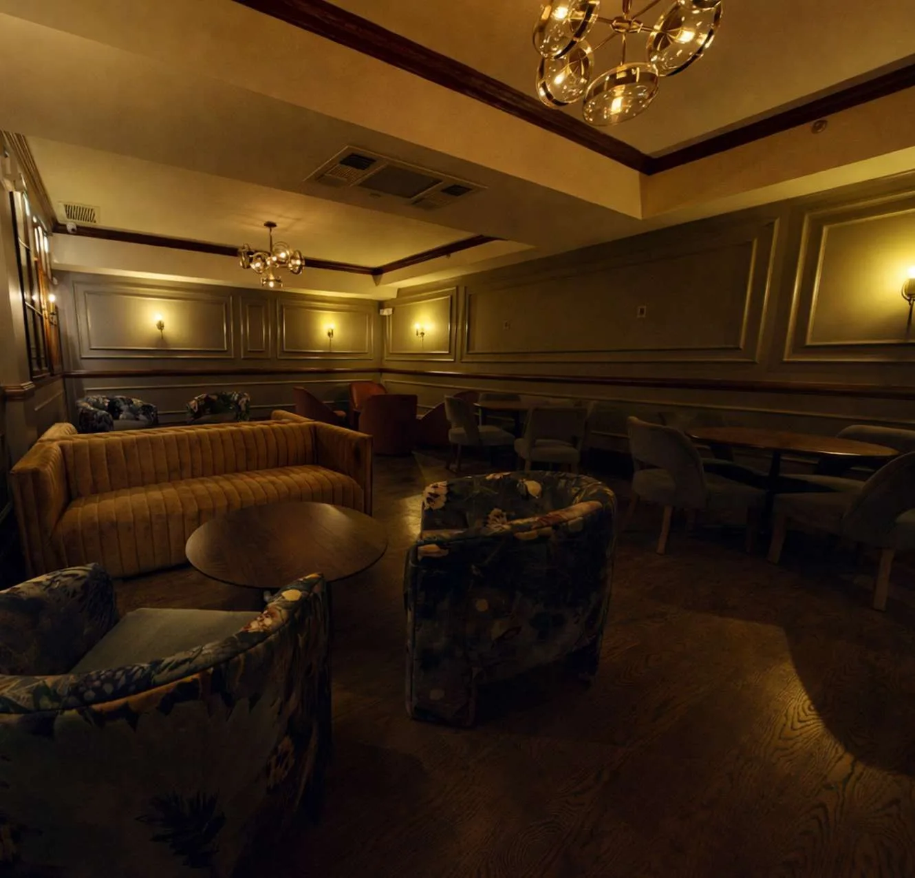 The private room with velvet sofa and warm sconce lighting